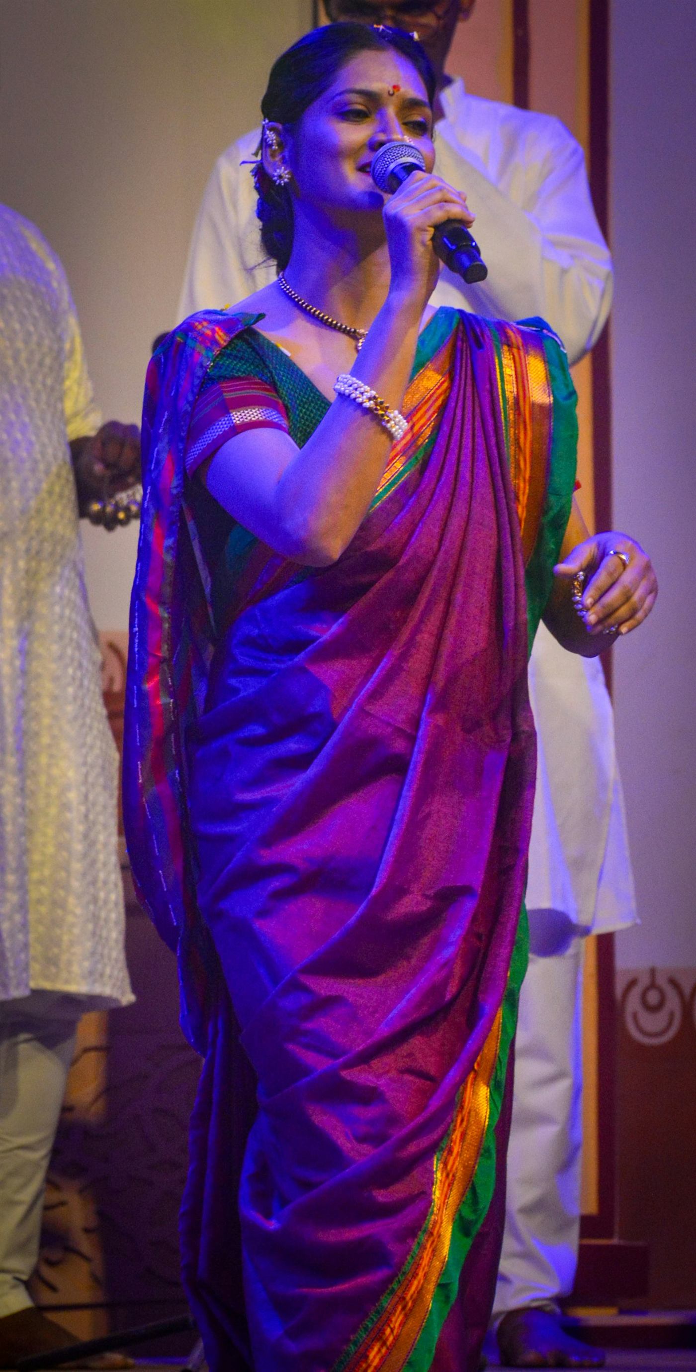 Indian classical vocalist in a sari singing into a concert microphone